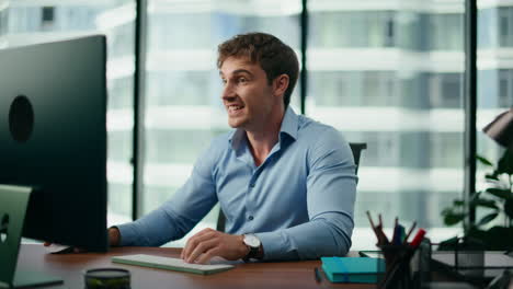 happy businessman celebrating triumph sitting at modern office table close up.