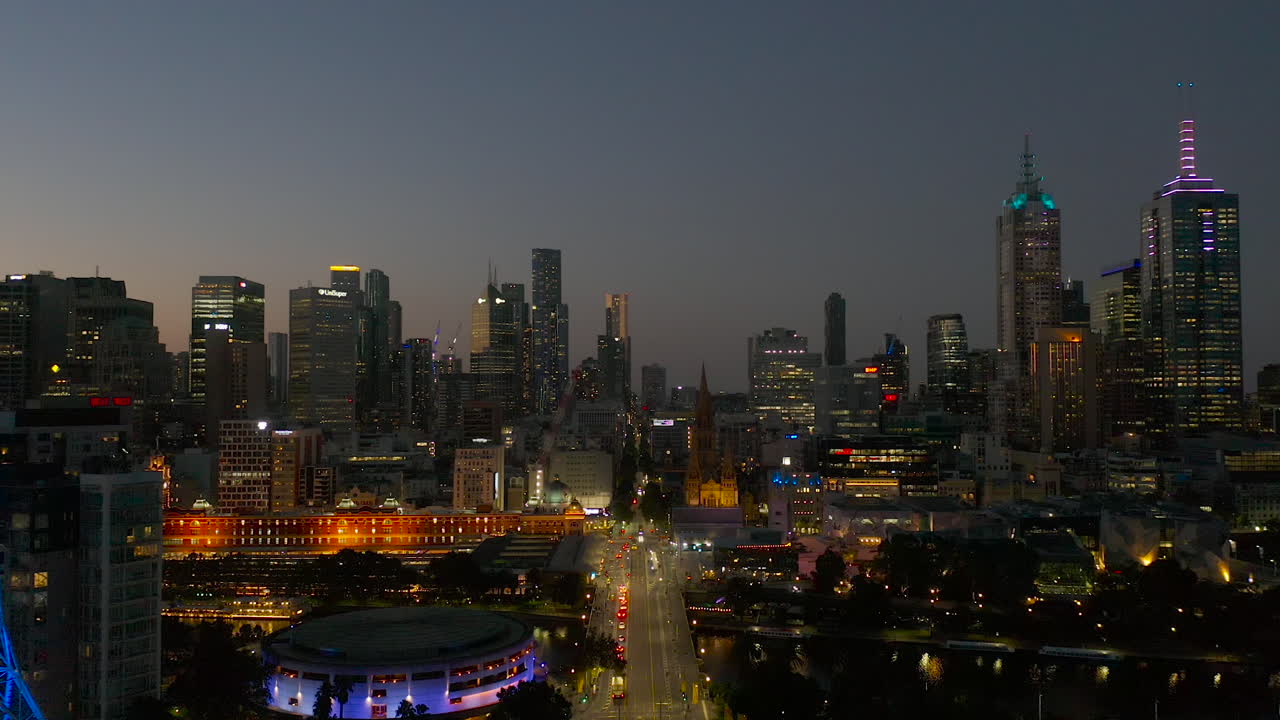 Prospettiva aerea al crepuscolo che si muove lungo St Kilda Road verso la Melbourne Art Spire e la stazione di Flinders Street.