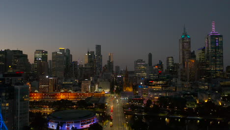 Perspectiva-Aérea-De-Seguimiento-Del-Anochecer-Bajando-Por-St-Kilda-Road-Hacia-Melbourne-Art-Spire-Y-Flinders-Street-Station