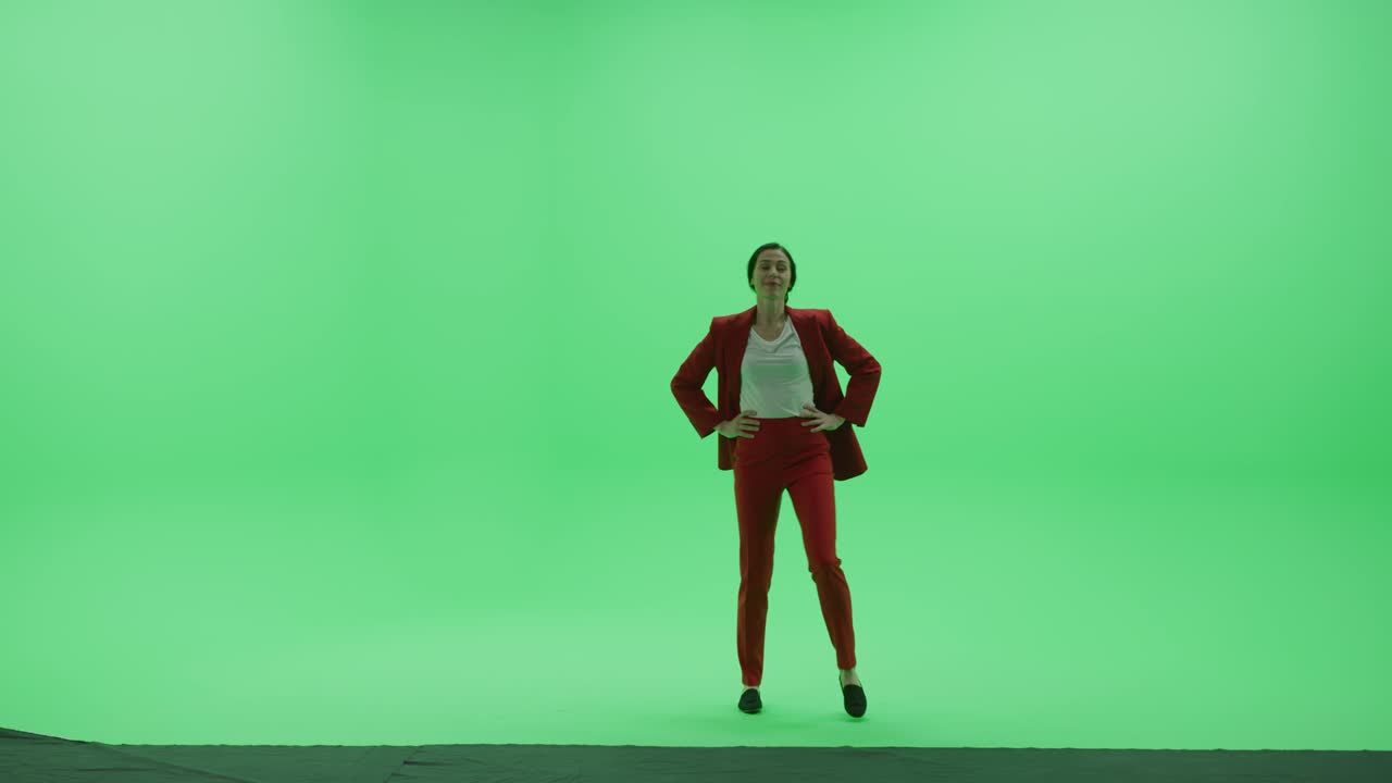 Studio Green Screen Chroma Key: Bella donna d'affari che indossa un elegante tailleur rosso sfila attraverso la stanza da destra a sinistra. Ripresa laterale