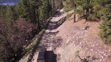 Ein-Dunkles-Suv-fahrzeug-Fährt-Langsam-Einen-Unbefestigten-Bergfeuerweg-Durch-Einen-Kiefernwald-Hinunter