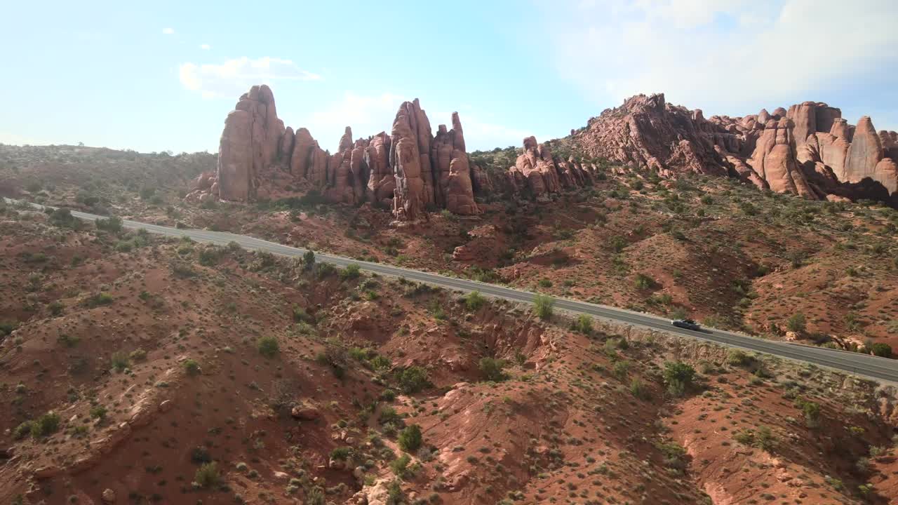 아치 국립 공원 의 파노라마적 인 아름다움을 포착 한 광범위한 드론  ⁇ , 그것 을 따라 여행 하는 식별 할 수 없는 자동차 와 함께 휘어지는 도로 를 특징 으로