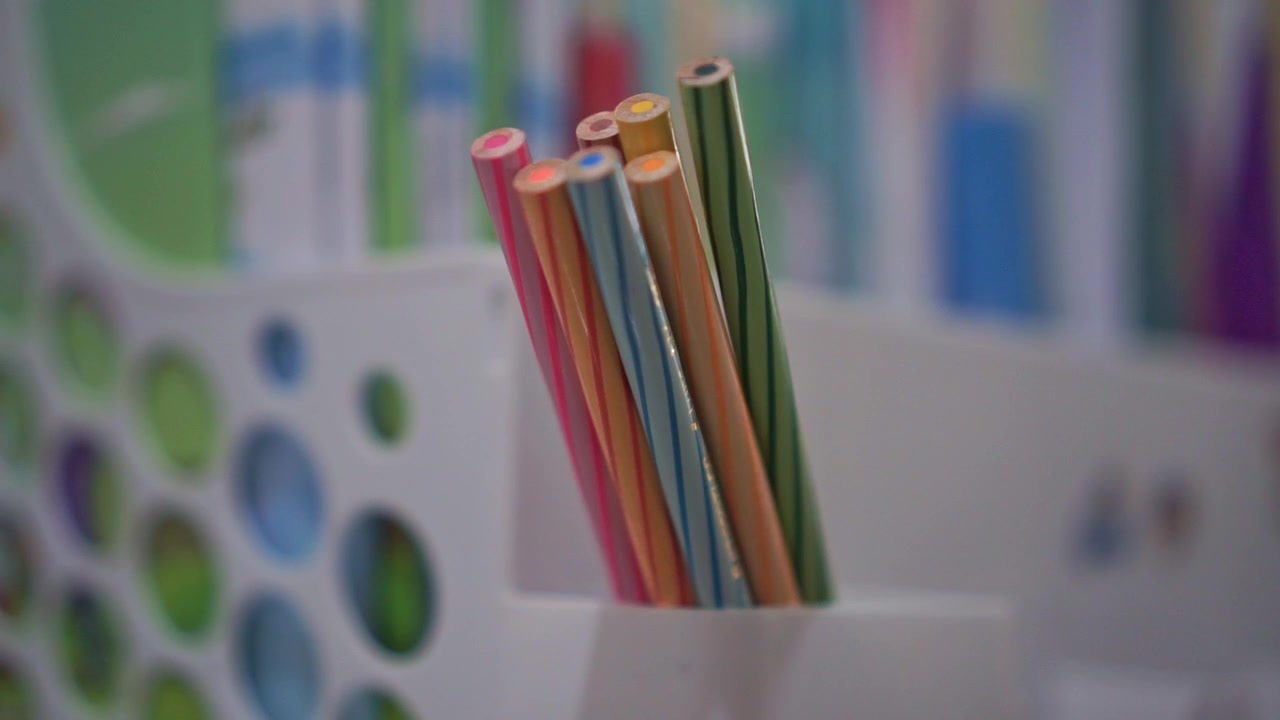 Mano colocando lápices de colores en un soporte, organización de materiales de arte, concepto de creatividad infantil y almacenamiento