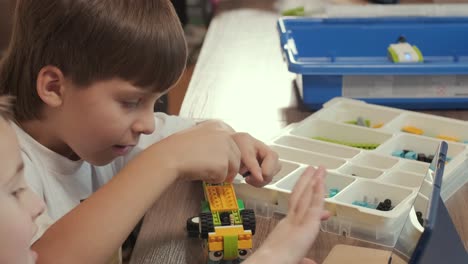 children intently focused on assembling parts from a robotics kit, with a tablet displaying instructions, promoting stem learning and creativity