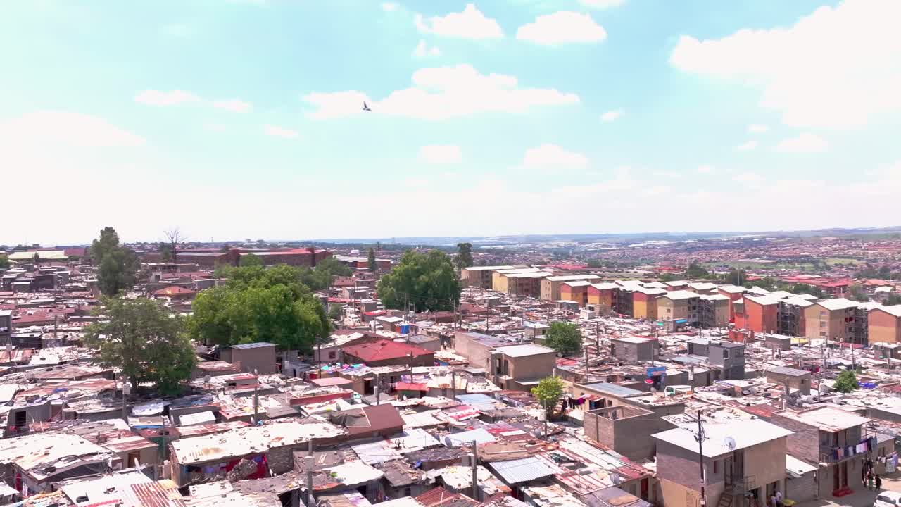 Aerial orbital panning shot of informal settlement in Alexandra Township, Johannesburg, South Africa, on a sunny day with scattered clouds
