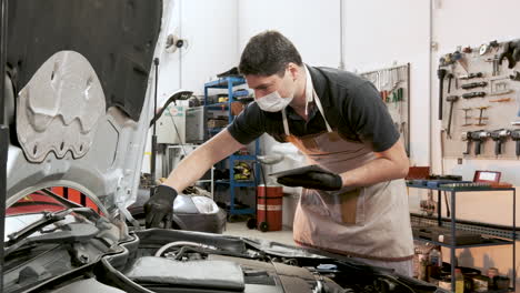 el mecánico de automóviles latino que usa una máscara verifica los elementos que figuran en el portapapeles