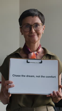 a woman holding a sign with a motivational quote about chasing dreams