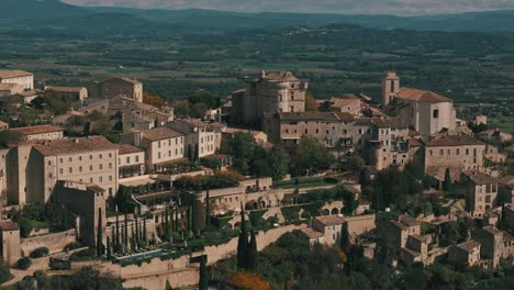 aerial tracking right of gordes, france, highlighting groves, vineyards, and autumn charm