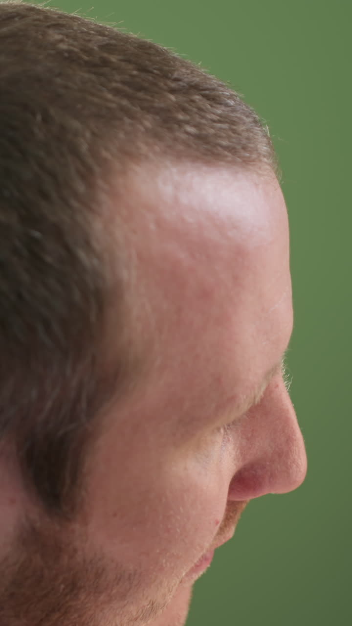 A close view of a technician in a white lab coat focusing intently on a task, looking into a microscope