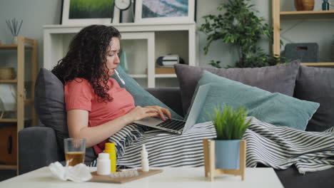 woman feeling sick, taking medicine and using laptop