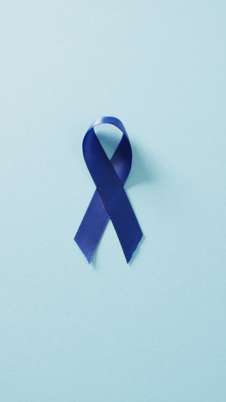복사 공간과 함께 희미한 파란색 배경에 파란색 대장암 인식 리본의 수직 비디오