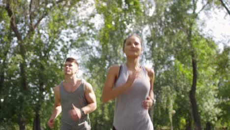 Sportliches-Junges-Paar,-Das-Zusammen-Im-Park-Läuft-Und-Dann-Nach-Dem-Laufen-Eine-Pause-Macht