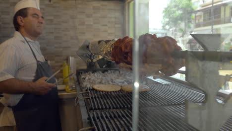 el cocinero está cocinando pizza de pollo a la parrilla y carne asada en la cafetería contra la ventana del espectáculo