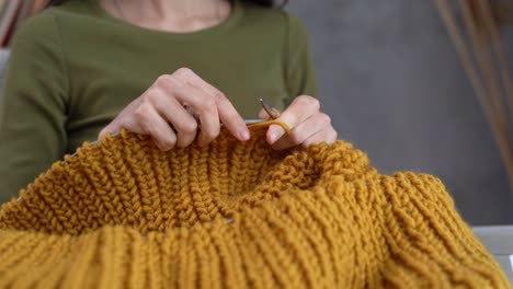 primer plano de manos femeninas tejiendo un suéter cálido, tejer con agujas y hilo de lana, hobby y concepto de costura