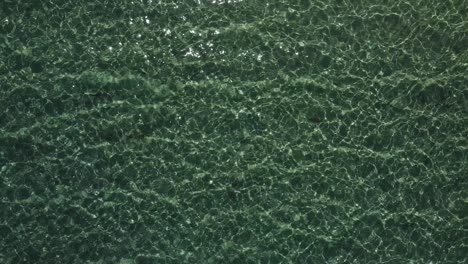 vista aérea de arriba hacia abajo de una bahía poco profunda con el agua brillando al sol
