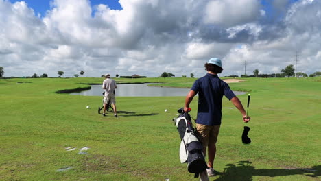 Young-boy-and-man-walking-together-on-green-golf-course-on-a-bright-sunny-day