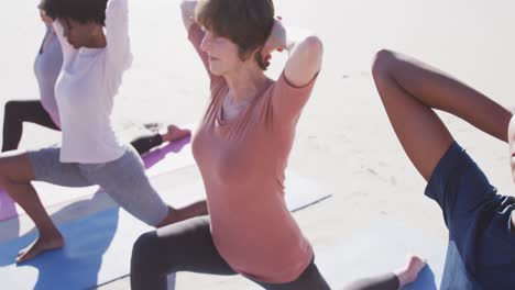 Multi-ethnic-group-of-women-doing-yoga-position-on-the-beach-and-blue-sky-background