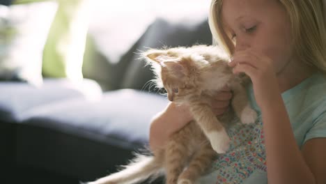 a little girl holding a kitten while it tries to escape