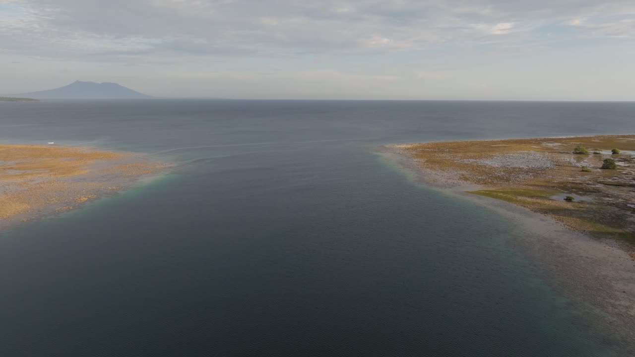 Droneflyvning over mangroveskog og kystlinje i West Bali nasjonalpark, med utsikt mot Menjangan Island over havvannet, som avslører tropisk skog, strandlinje og avsidesliggende indonesisk landskap