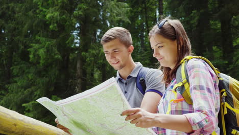 tourism and active lifestyle a young couple looks at the map stand in a picturesque place on a summe