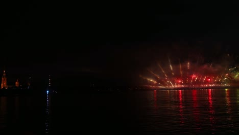 festive colorful fireworks and illumination in dark sky with beautiful reflection in water. holiday scarlet sails