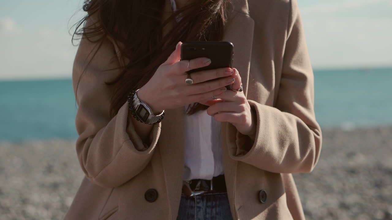 женщина пользуется телефоном на пляже.