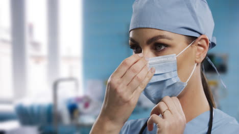 female caucasian surgeon adjusting her face mask in hospital