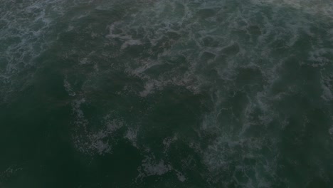 Aerial-view-tilting-over-waves-on-the-Atlantic-Ocean,-cloudy-sunset-in-Portugal