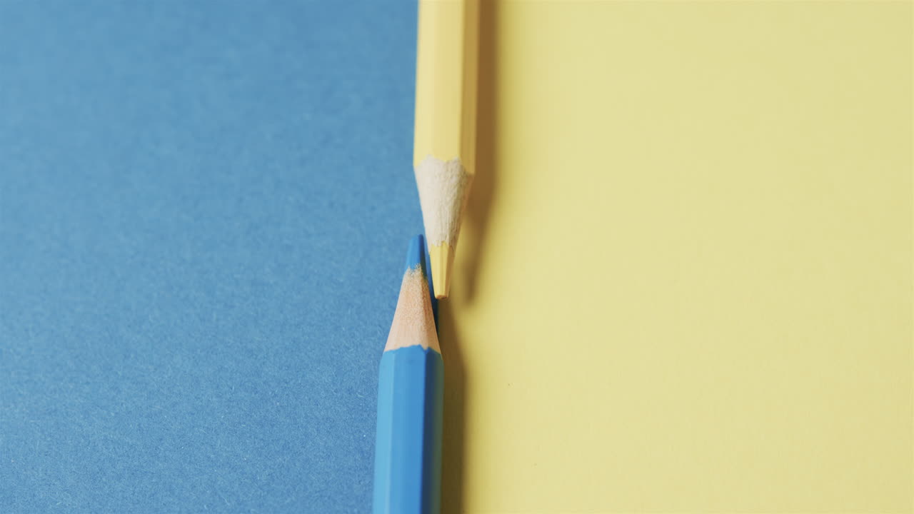 노란색과 파란색 크레이온의 클로즈업과 파란색과 노란색 배경의 복사 공간, 슬로우 모션