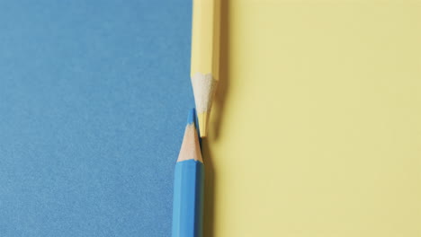 primer plano de lápices de colores amarillos y azules con espacio de copia en fondo azul y amarillo, en cámara lenta