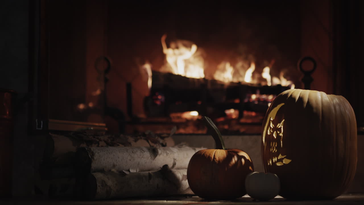 큰 빛나는 호박은 불타는 벽난로에 의해 황혼에 놓여 있습니다. 집은 할로윈, 가을 휴일을 위해 장식되어 있습니다