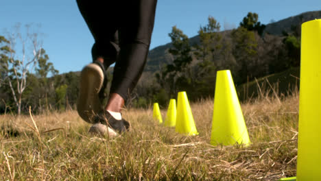 Low-section-of-woman-running-through-training-cones
