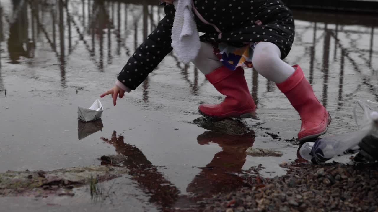 Little Girl Takes The Paper Boat Out On The Water. close up