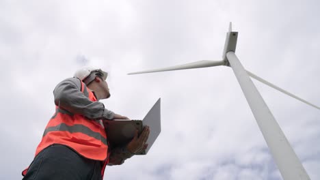 progressive engineer working with the wind turbine, with the sky as background.