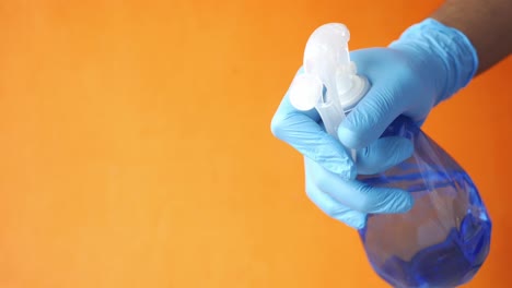 cleaning spray bottle held by gloved hands