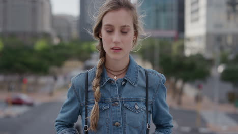 portrait young independent blonde woman student in city looking confident at camera wearing denim jacket urban cityscape background