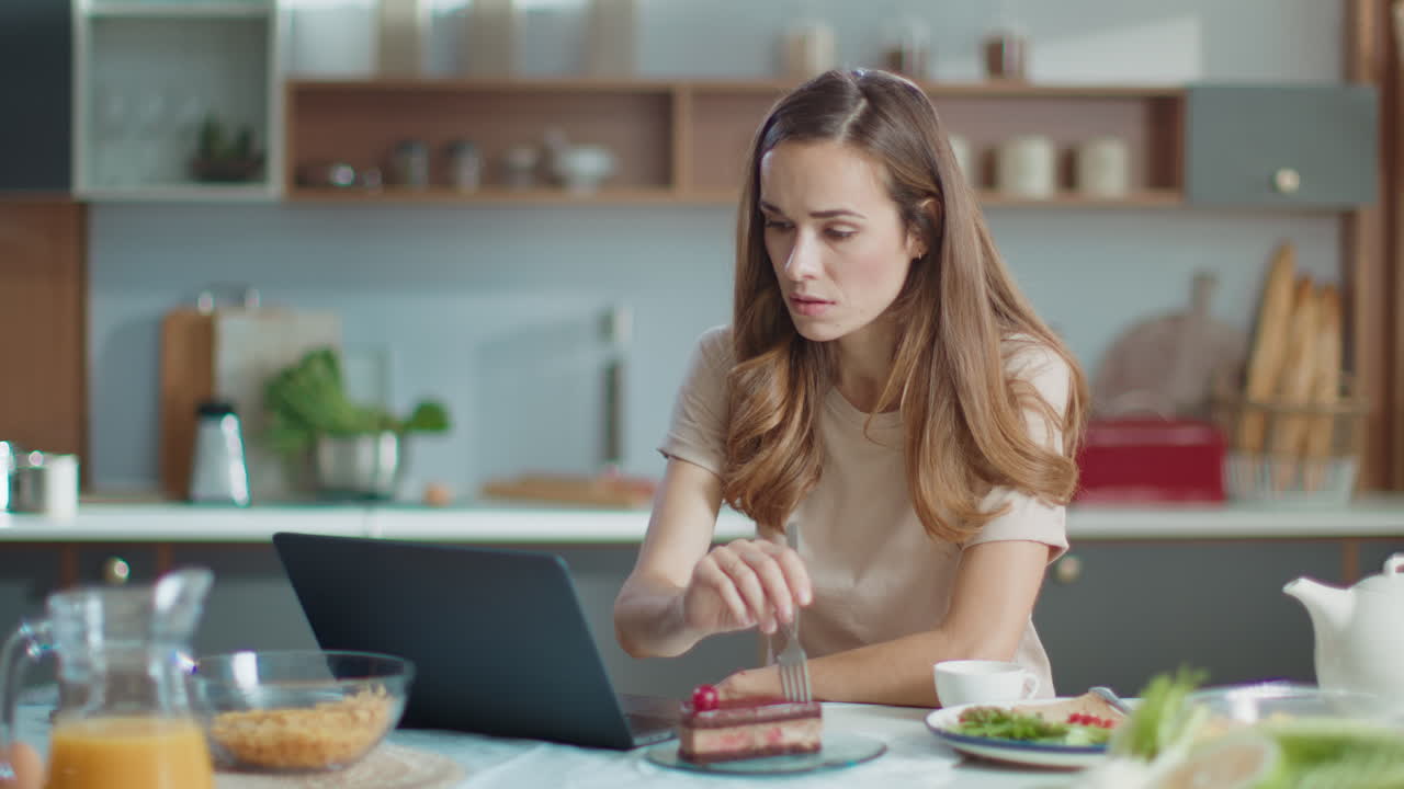 Businesswoman using laptop while eating cake