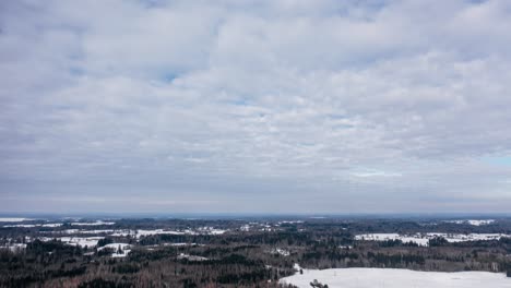 aerial cloud timelapse over the forest in snow covered winter day. drone hyperlapse in overcast countryside landscape.