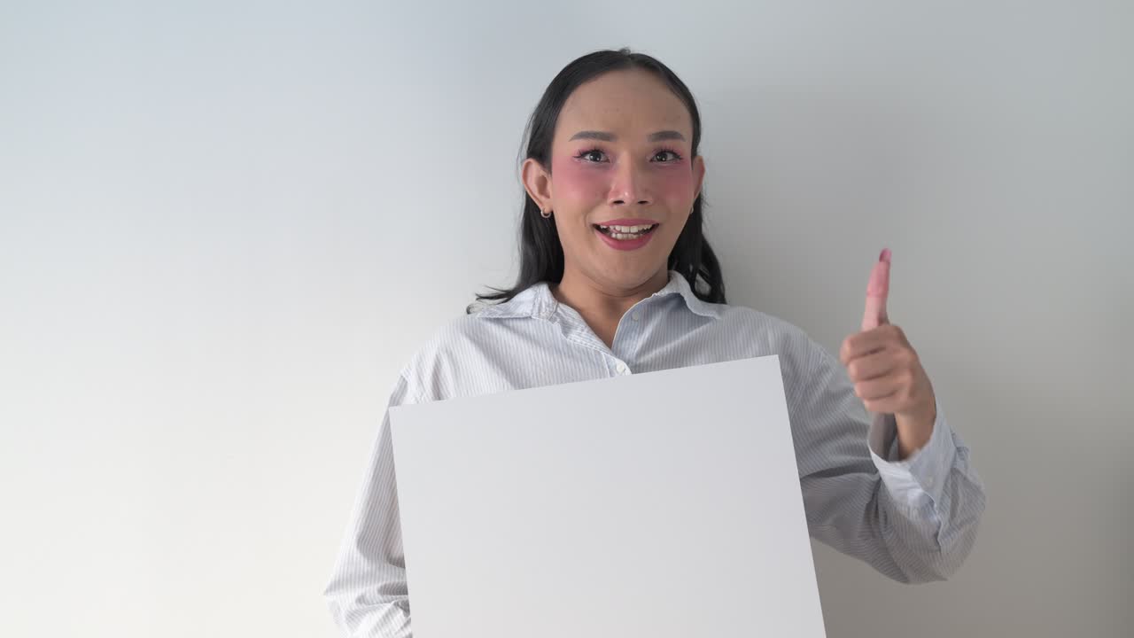 Thai transgender person holding white board and giving thumbs up while smiling and pointing finger
