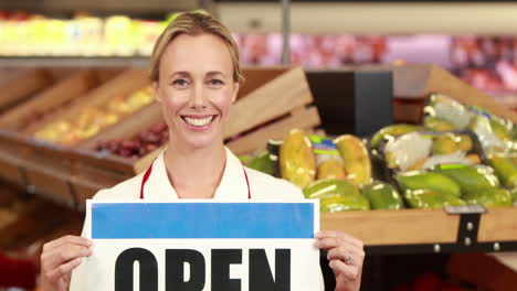 smiling worker holding open sign