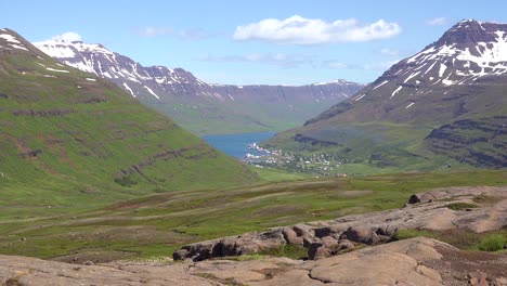 establishing shot of a high mountain fjord in iceland the village of seydisfjordur distant