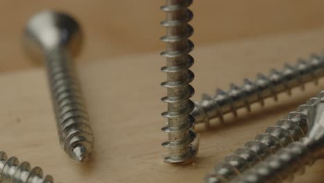 macro view of rotating screw falling out of wooden beam in slow motion