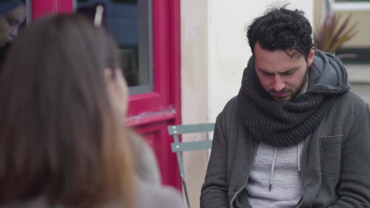 우울하고 불행한 남자가 여자친구의 말을 듣고 있는 동안 슬픈 얼굴로 반대편에 앉아 있습니다.