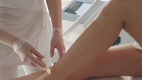 laser hair removal treatment in aesthetic clinic cosmetologist applying gel on leg of adult woman