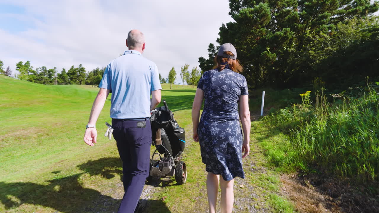 Golf players walking with clubs and talking on golf course