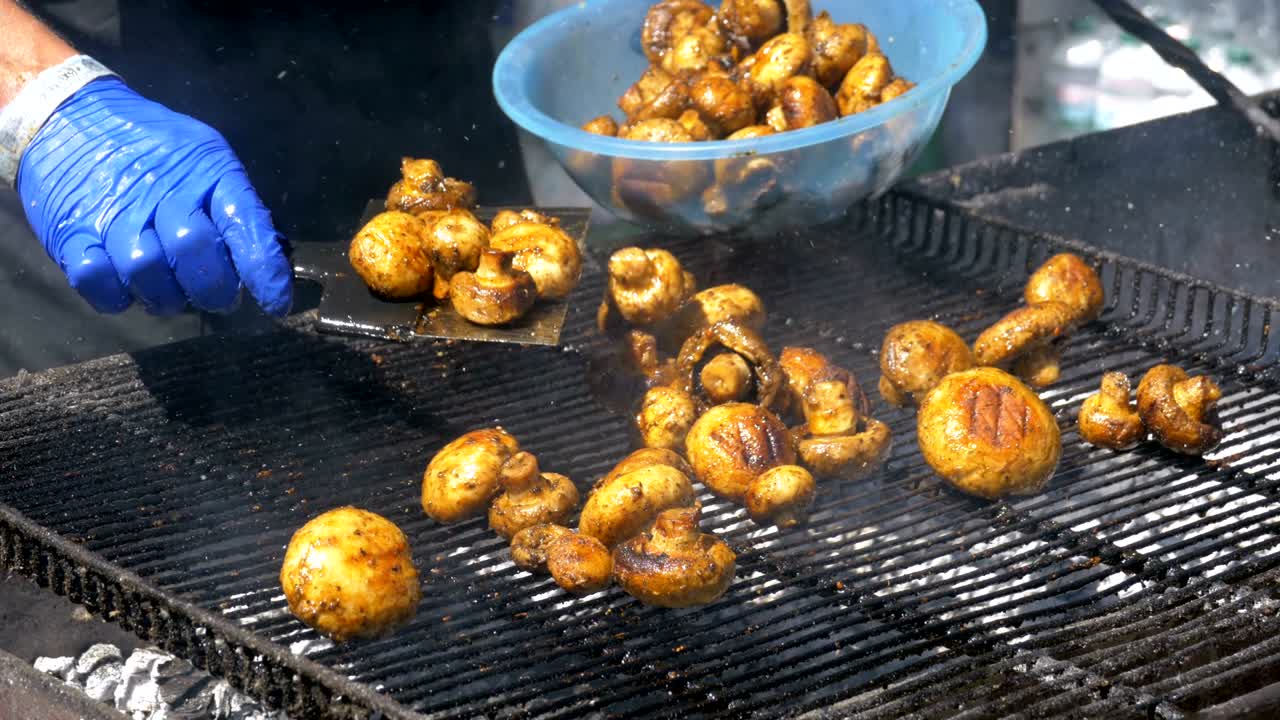 요리사는 그릴에 버섯을 준비합니다. 바베큐 파티