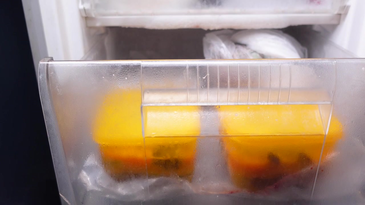 Mano che apre il cassetto del congelatore contenente contenitori per alimenti