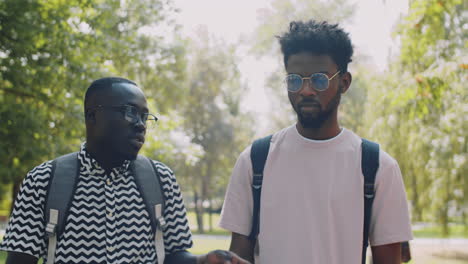 dos estudiantes universitarios negros charlando y caminando en el parque