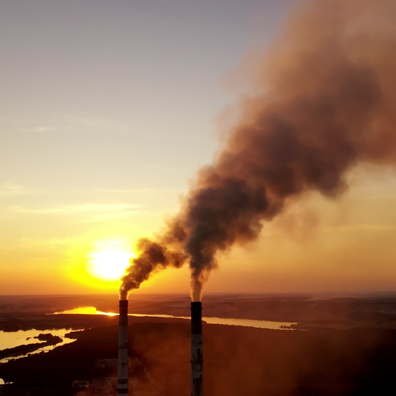Air pollution over power plant at sunset. Violation of environmental contamination of the atmosphere the remnants of combustion near the evening river.