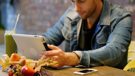 man using digital tablet with glass of juice on table